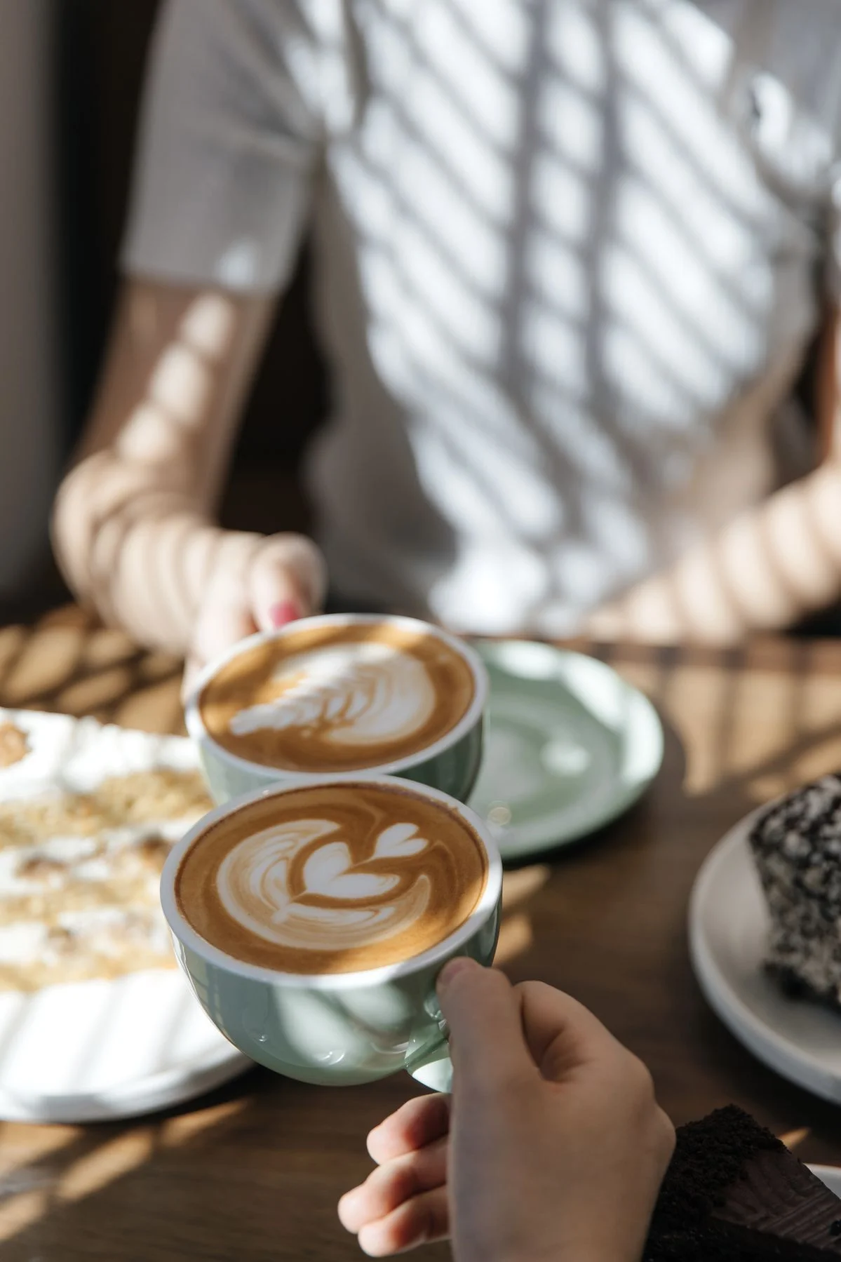 Zwei Personen mit Cappuccino und Latte Art an einem Tisch